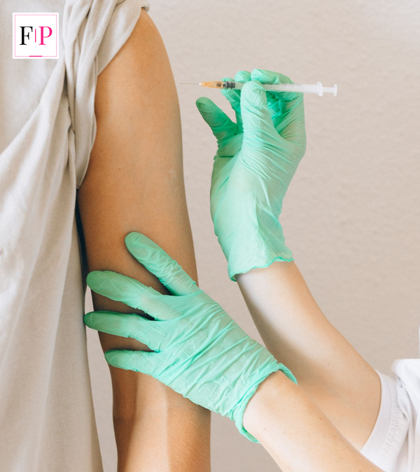 Pharmacist giving a Boots flu jab into a patient's upper arm