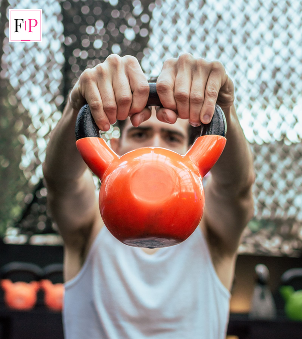 Man holding an orange kettlebell during Hyrox UK strength training