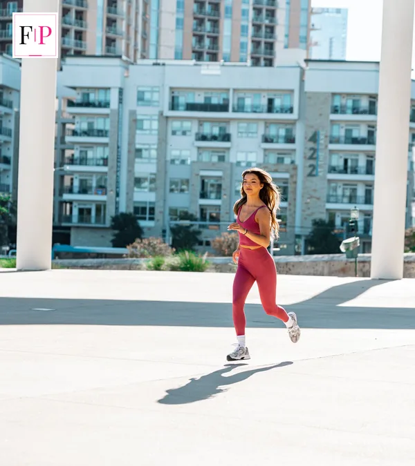 10K Training Plan: 8-Week Beginner Plan to Race Day A woman running on a city street in training kit — following a 10k training plan
