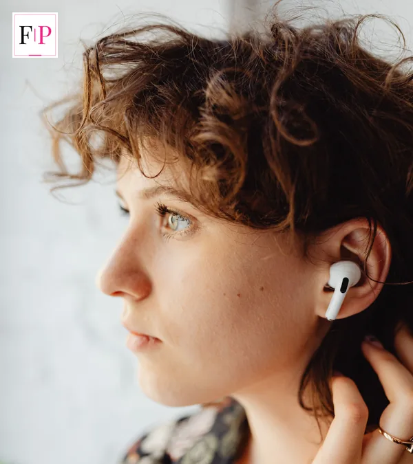 A woman in profile wearing a white wireless earbud and listening — airpods pro 3 listening and fit