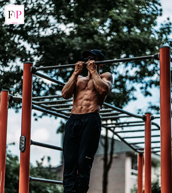 Man training on an outdoor calisthenics bar — dead hang exercise outdoors