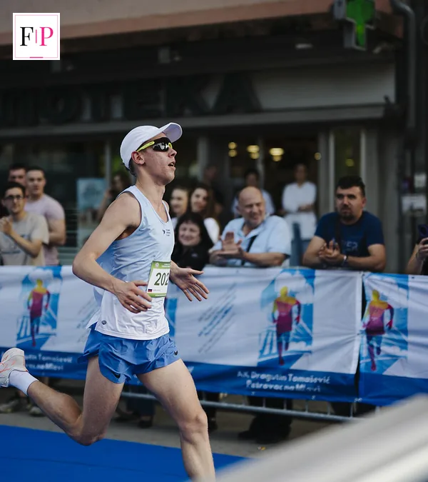 A runner crossing the finish line of a city race — the race-day goal of a half marathon training plan