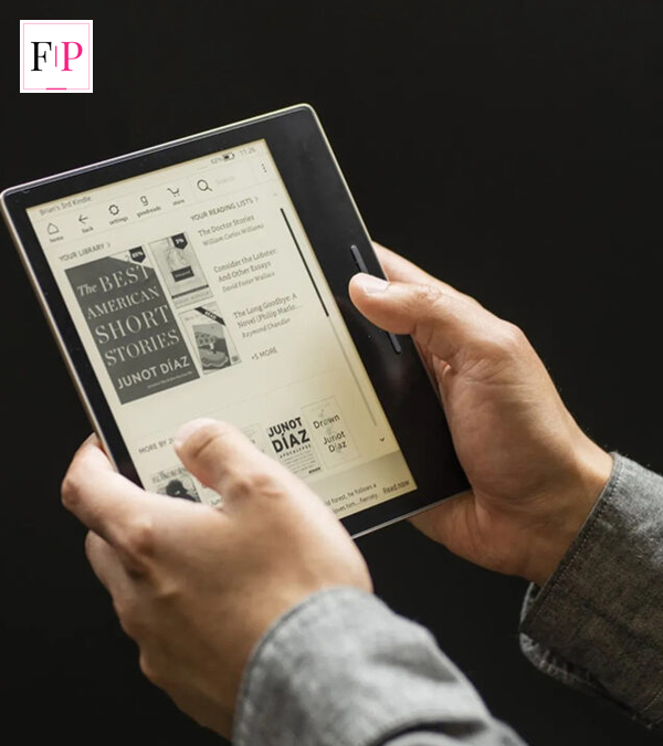Hands holding an e-reader showing a book library — the new Kindle Paperwhite is perfect for one-handed reading