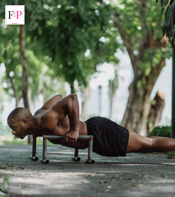 Weighted Vest Walking: 7 Benefits, Weights and Safety Tips Man doing push-ups on parallettes in a park — outdoor training alongside weighted vest walking
