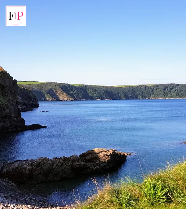 Green cliffs and blue sea on the Welsh coast at Little Haven — the Welsh roots behind who is michael sheen