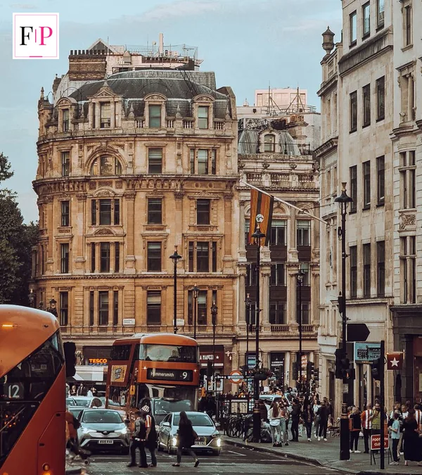 People walking on a busy London street with double-decker buses at dusk — the London roots behind who is ross kemp